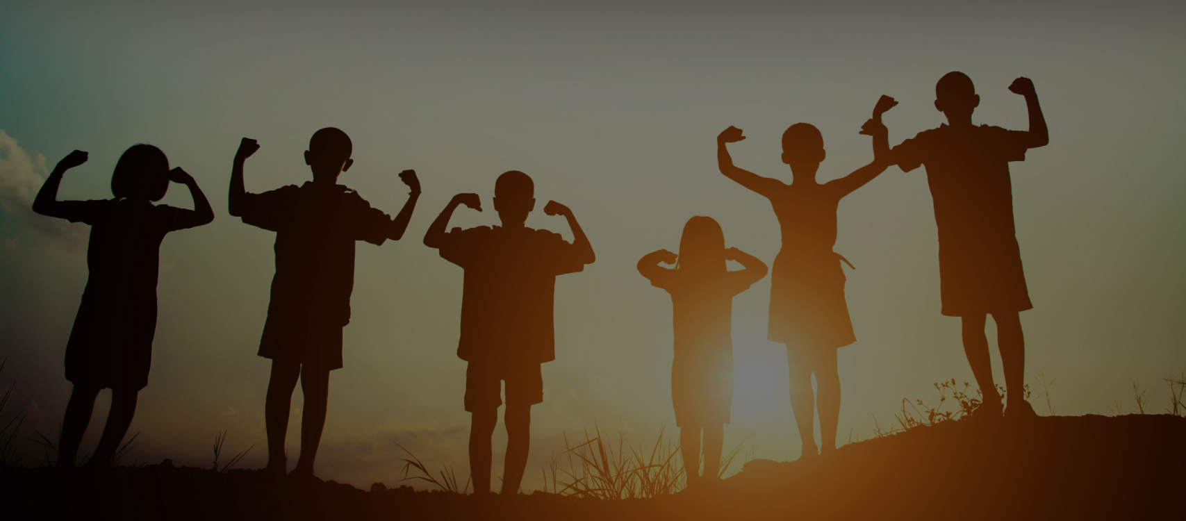 Silhouettes of children at sunset, arms raised
